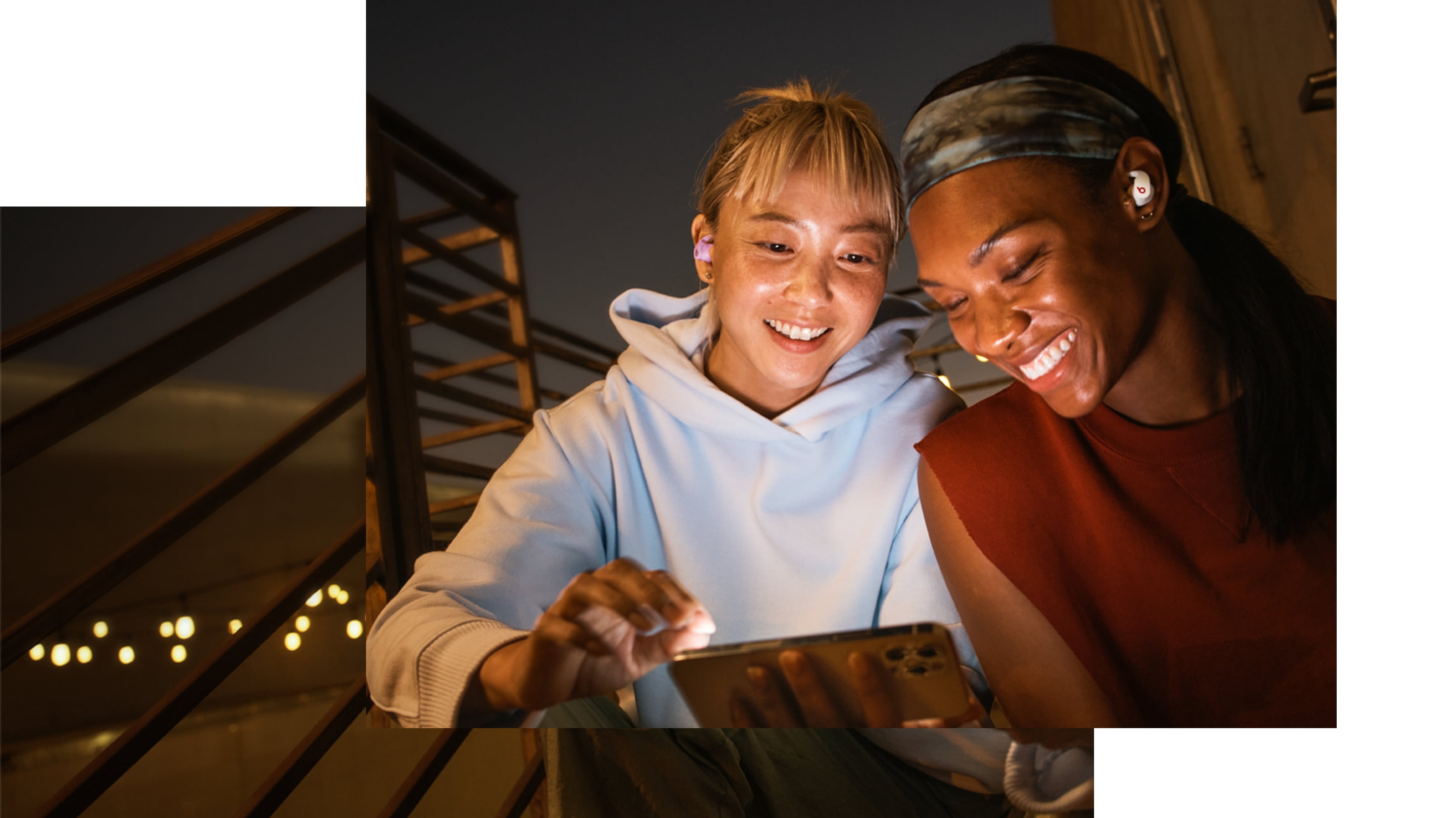 Two people looking at an iPhone wearing Beats Studio Buds