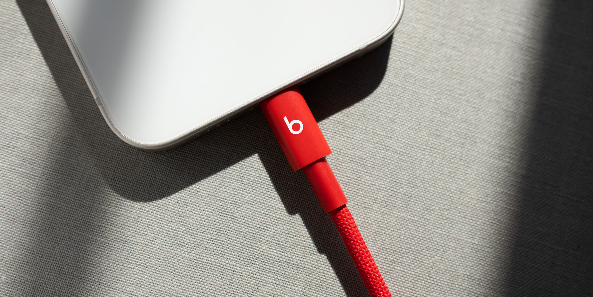 Person plugging a Beats USB-C to Lightning Woven Cable into a compatible device. 